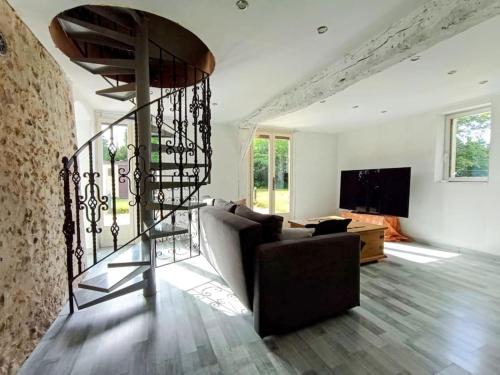 sala de estar con sofá y escalera de caracol en Longère Normande - Center Parcs - Proximité GR, en Bourth