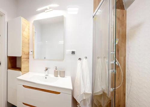 ein weißes Bad mit einem Waschbecken und einer Dusche in der Unterkunft WOART Apartments in Sosnowiec