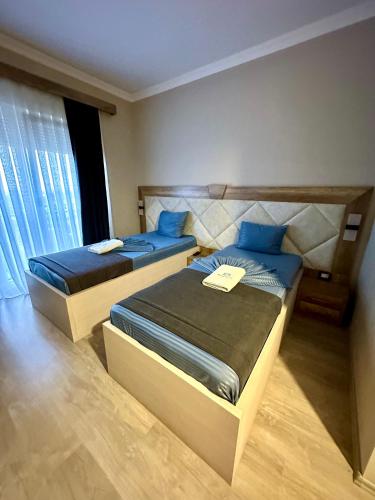 two beds with blue pillows in a bedroom at Hotel Borea in Peje