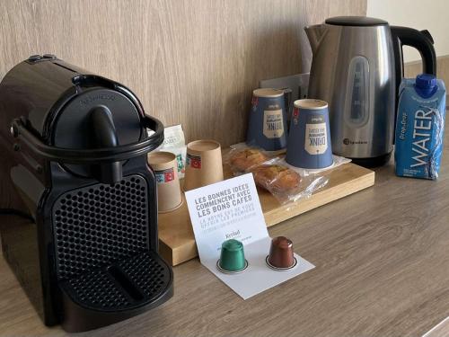 a coffee maker sitting on a table with a coffee pot and a bagel at Kyriad Prestige Residence & Spa Cabourg-Dives-sur-Mer in Dives-sur-Mer