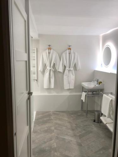 a bathroom with three white shirts hanging on a wall at Les Grands Jardins Lodge in Giverny