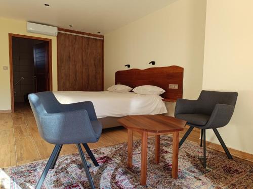 um quarto com uma cama com 2 cadeiras e uma mesa em AU JASMIN DE NUIT em La Plaine des Palmistes