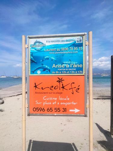 a sign on the beach in the sand at Courbaril Résidence in Les Trois-Îlets
