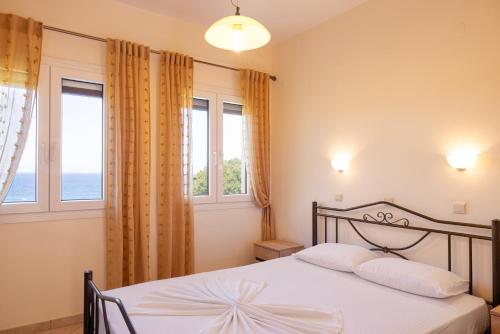 a bedroom with a bed with two pillows and two windows at Marina Apartments in Kokkari
