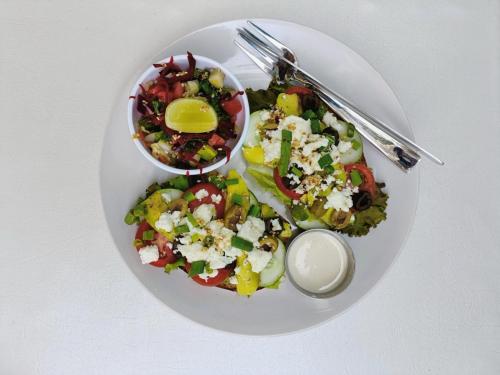 une assiette blanche avec une salade et un bol de nourriture dans l'établissement Nature's View Homestay, Travellers, à McLeod Ganj