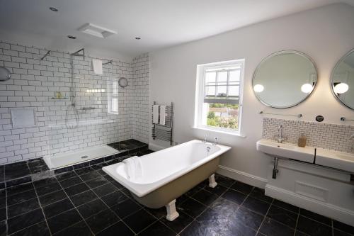 Baño blanco con bañera y lavamanos en The Castle Inn Bradford on Avon, en Bradford on Avon