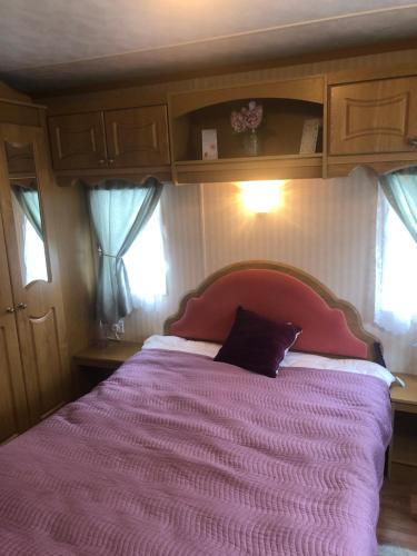 a bedroom with a large bed with a pink blanket at Màire’s Mobile Home in Falcarragh