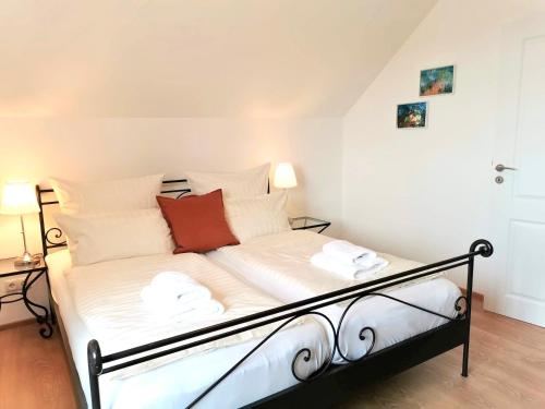 a bed with white sheets and red pillows in a room at Landhaus Vogel - helle und lichtdurchflutete Maisonette-Ferienwohnung in Wasserburg am Bodensee