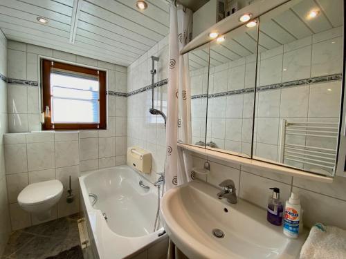 La salle de bains est pourvue d'une baignoire, de toilettes et d'un lavabo. dans l'établissement Ferienwohnung Blumenoase - gemütliche Ferienwohnung zwischen Allgäu und Bodensee, à Sigmarszell