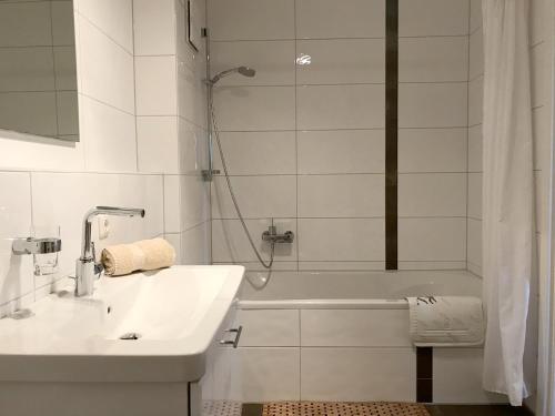 uma casa de banho branca com um lavatório e um chuveiro em Ferienwohnung Seetraum - Hoch über dem See, großzügig mit großem Balkon em Kressbronn am Bodensee