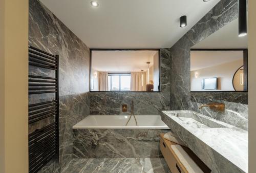 a bathroom with a tub and a sink and mirrors at Fahrenheit Seven Courchevel in Courchevel