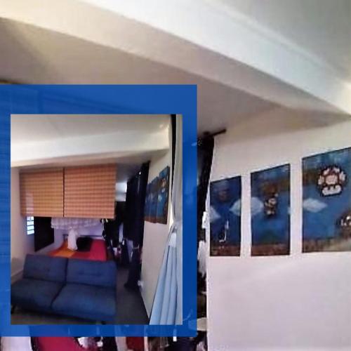 Habitación con sofá azul y cuadros en la pared. en Studio avec sa terrasse et son jardinet dans un écrin de verdure, en Les Abymes