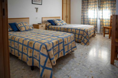 a hotel room with two beds with blue and yellow sheets at Pensión Dos Hermanas in Bolaños de Calatrava