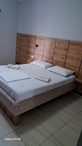 a bedroom with a large bed with a wooden headboard at Hotel Marigona in Shëngjin