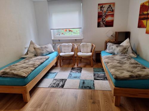 twee bedden in een kamer met stoelen en een raam bij Schöni´s Zimmer in Abstatt
