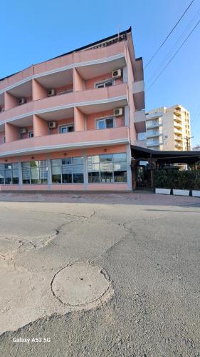 a large pink building with a street in front of it at Hotel Marigona in Shëngjin