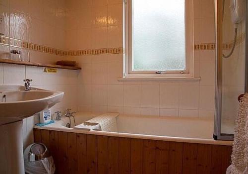 a bathroom with a tub and a sink and a window at Cairn Shiel in Achnasheen