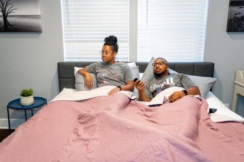 two people are sitting in a bed at Vibrant Vacation Escape with Fast WIFI and KING BED Close to Downtown Houston! in Houston