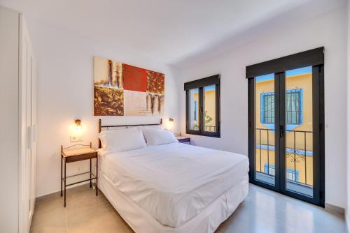 ein weißes Schlafzimmer mit einem Bett und zwei Fenstern in der Unterkunft Parkview Apartments 2 in Marbella