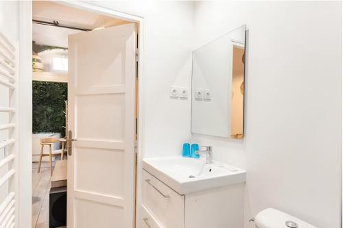 ein weißes Badezimmer mit Waschbecken und Spiegel in der Unterkunft Secret Jungle Bordeaux Chartrons - Hyper-Centre Jacuzzi Bain Balnéo & Home cinéma in Bordeaux
