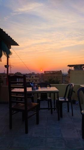 a table and chairs on a roof with the sunset at Relax Inn Jaisalmer in Jaisalmer