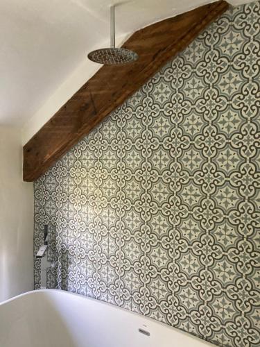 uma casa de banho com uma parede de azulejos e uma banheira em Avondale em Llangollen