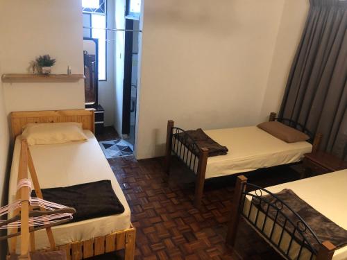 a room with three beds in a room at Little Cozy Homestay in Kota Bharu