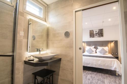 a bathroom with a sink and a bed at The Originals City, Hôtel Rive Droite, Albi "Quartier Madeleine" in Albi