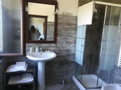 ein Bad mit einem Waschbecken, einer Dusche und einem Spiegel in der Unterkunft Casale Nido dell'Aquila in Squille