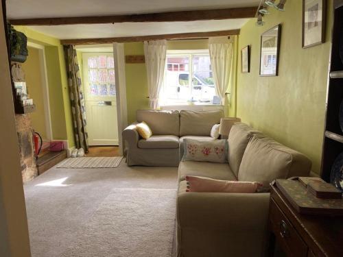 a living room with two couches and a window at Lemon Cottage in Hatherleigh