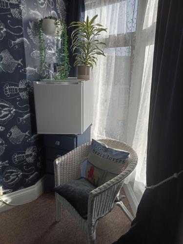 a chair with a pillow sitting next to a window at Marjune Guest House in Weymouth