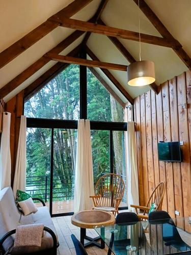 a living room with a table and chairs and a large window at Les Chalets Costa Rica in Zarcero