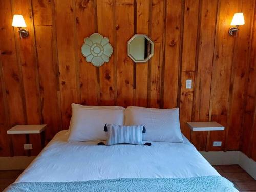 a bedroom with a white bed with wooden walls at Les Chalets Costa Rica in Zarcero