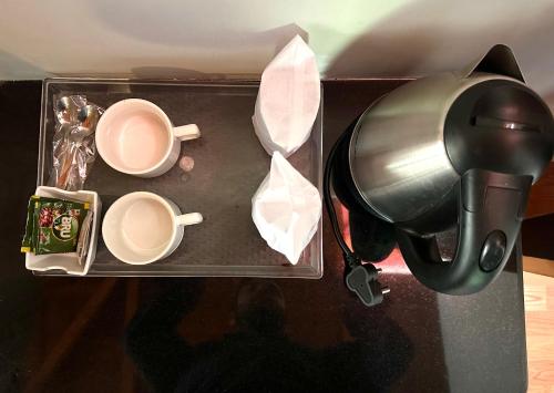 a tray with two cups and a coffee maker at The little nest Home Stay in Bhīm Tāl