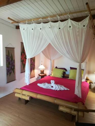 a bedroom with a large bed with a canopy at Bungalow atypique Ti Bambou à 500m de la plage in Sainte-Anne