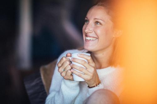 a woman smiling while holding a white coffee cup at Hôtel L'Arboisie in Megève