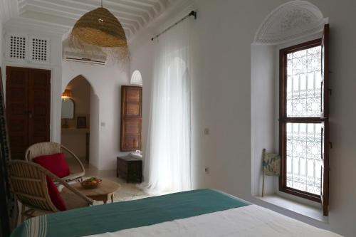a bedroom with a bed and a table and a window at RIAD DAR DAR in Marrakesh