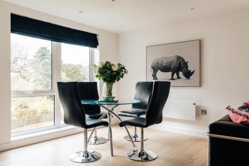a living room with a glass table and two black chairs at Charlecote House in Bath