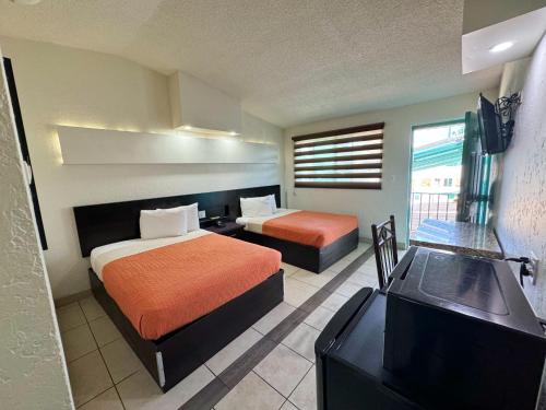 a hotel room with two beds and a television at REAL INN de Tijuana in Tijuana