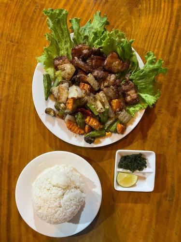 two plates of food with rice and vegetables on a table at Phong Nha Dawn Home in Phong Nha