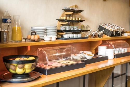 a buffet with plates and food on a table at The Originals City, Hôtel Rive Droite, Albi "Quartier Madeleine" in Albi