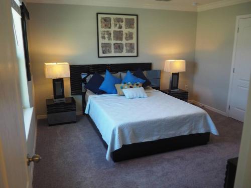 a bedroom with a bed with blue pillows and two lamps at Luxurious Farm Style House in Kissimmee