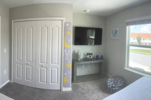 a bedroom with a bed and a door with a tv at Luxurious Farm Style House in Kissimmee