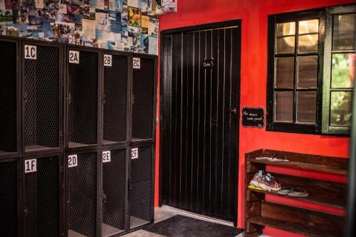 a row of lockers in a room with a red wall at House of Lion Hostel in Pantai Cenang