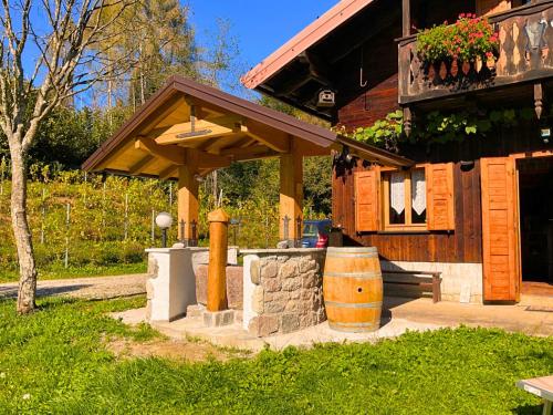 a wooden building with a barrel in front of it at Chalet Relax Tra Le Vigne in Forni di Sotto