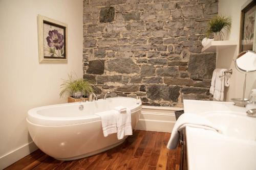 a bathroom with a white tub and a stone wall at Royal Dalhousie in Quebec City