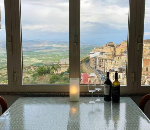 two bottles of wine sitting on a table in front of a window at Mineo Townhouse with incredible views of Mt Etna in Mineo