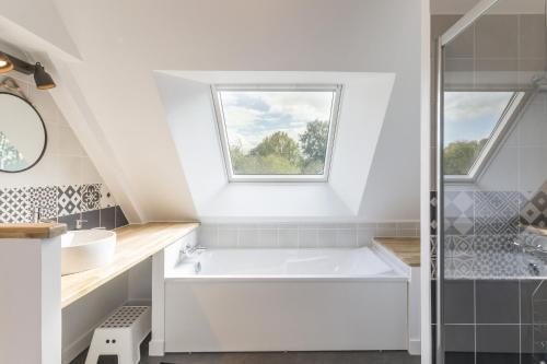 a bathroom with a tub and a sink and a window at Au jardin de Capucine in Bricqueville-sur-Mer
