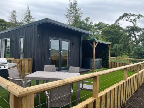 a black shed with a table and chairs on a fence at East Kip - Dog Friendly in Penicuik