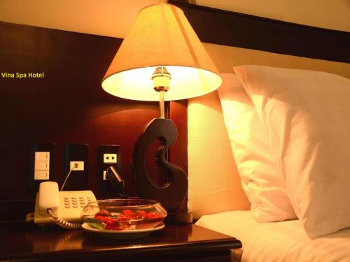 a table with a lamp and a bowl of fruit and a phone at Việt Nam Hotel in Hue